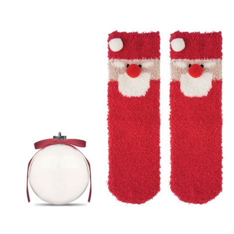Paire de chaussettes rouges à motif Père Noël présentée dépliée à côté de la boule transparente vide ornée de son ruban rouge.