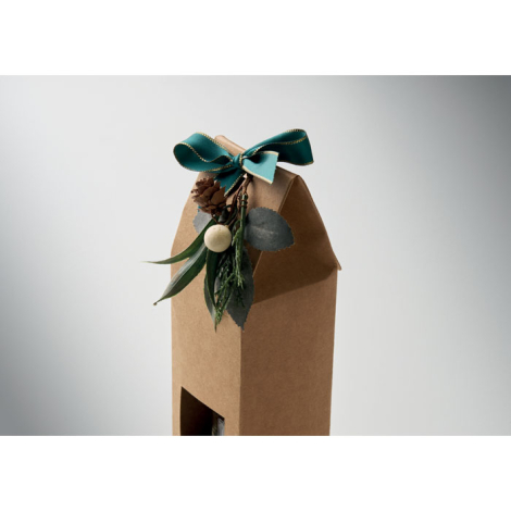 Détail de la partie supérieure de la boîte kraft montrant le nœud vert bordé de doré, la pomme de pin et les éléments végétaux d