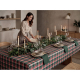 Une femme dresse une longue table recouverte de la nappe à carreaux verts, rouges et blancs, entourée de vaisselle, de verres, d Une femme dresse une longue table recouverte de la nappe à carreaux verts, rouges et blancs, entourée de vaisselle, de verres, d