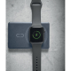 Montre connectée noire posée sur la zone circulaire d’une batterie externe bleu foncé, avec symbole de charge vert affiché sur s