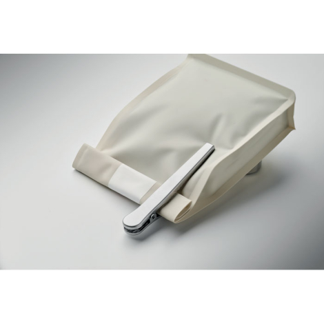 Sachet beige ouvert posé sur une surface claire, avec cuillère doseuse en acier inoxydable fixée sur le bord replié à l’aide de 