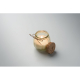 Bougie allumée dans un pot en verre clair à reliefs, avec ficelle en jute nouée autour du col et couvercle en liège posé contre Bougie allumée dans un pot en verre clair à reliefs, avec ficelle en jute nouée autour du col et couvercle en liège posé contre
