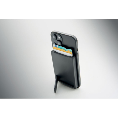 Vue de trois quarts d’un smartphone maintenu en position verticale par le support déplié du porte-cartes magnétique, avec plusie