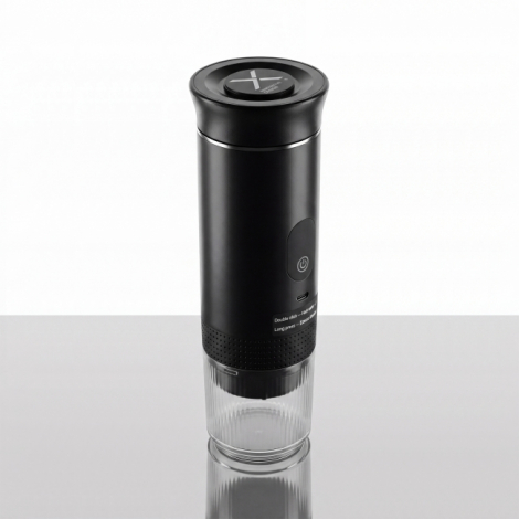 Machine à expresso portable noire vue de trois quarts avec bouton d'alimentation, port USB-C et gobelet transparent.