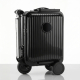 Vue de trois quarts d'une valise-trottinette noire à coque rigide brillante et rainures verticales, avec guidon replié contre le