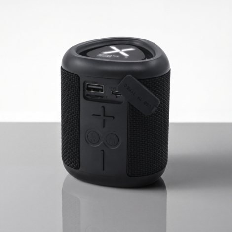 Enceinte Bluetooth noire présentée de face, avec grille textile, boutons de commande en relief et cache de protection relevé lai
