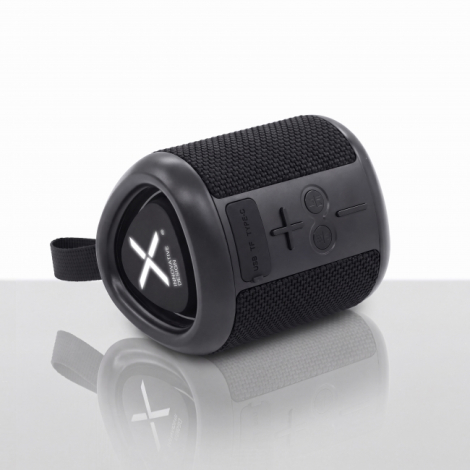Vue de trois quarts d'une enceinte Bluetooth noire posée horizontalement, avec revêtement textile tressé, commandes latérales en