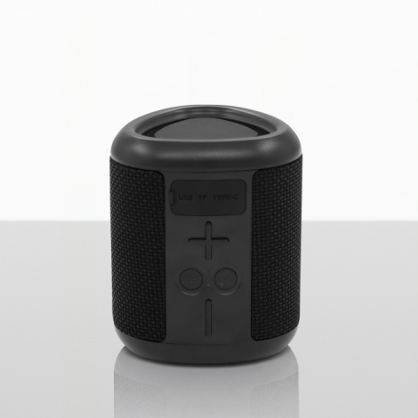 Vue de face d'une enceinte Bluetooth cylindrique noire posée verticalement, présentant un panneau central avec boutons de comman