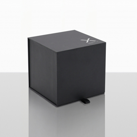 Vue de trois quarts d'un coffret cadeau noir cubique fermé, avec surface mate, marquage blanc discret dans un angle du couvercle