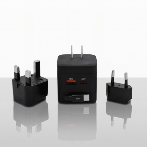 Vue de trois quarts d'un adaptateur de voyage noir accompagné de deux embouts de prise amovibles, l'un à trois broches et l'autr