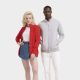 Deux mannequins, une femme et un homme, présentent la veste zippée en deux coloris. La femme porte une version rouge ouverte sur Deux mannequins, une femme et un homme, présentent la veste zippée en deux coloris. La femme porte une version rouge ouverte sur