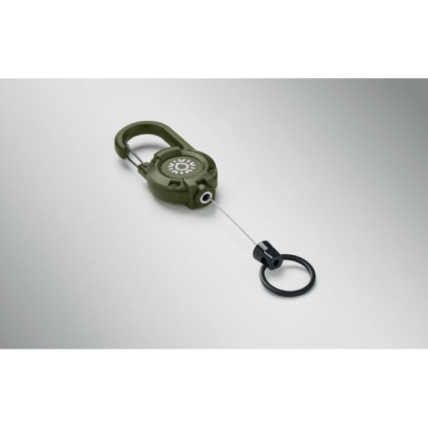Porte-badge rétractable vert kaki posé à plat, avec un graphisme blanc sur le boîtier circulaire et un câble métallique déroulé 