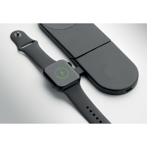 Vue rapprochée d'une montre connectée noire posée sur le chargeur circulaire latéral de la station de recharge, avec un symbole 