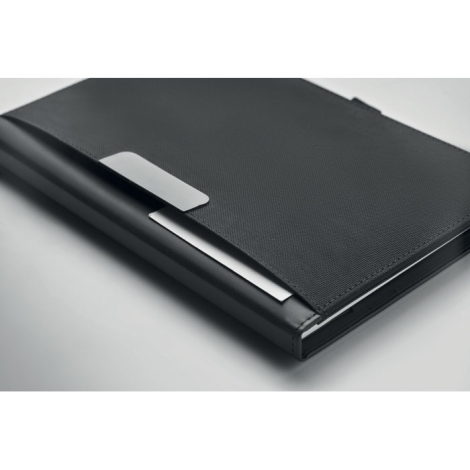Vue rapprochée du conférencier noir mettant en évidence la texture quadrillée de sa couverture, les coutures périphériques et la
