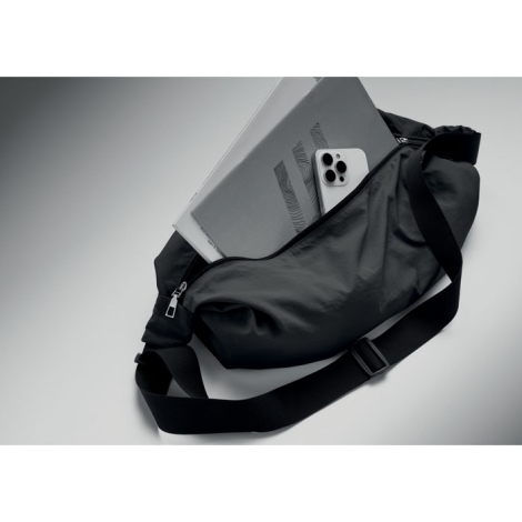 Sac urbain noir ouvert, présenté avec un ordinateur portable gris et un smartphone argenté partiellement insérés dans son compar