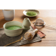 Set à matcha disposé sur une table en bois, avec un bol en céramique contenant une préparation verte mousseuse, un fouet en bamb Set à matcha disposé sur une table en bois, avec un bol en céramique contenant une préparation verte mousseuse, un fouet en bamb