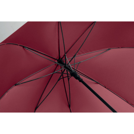 Gros plan sur l'intérieur d'un parapluie bordeaux ouvert, montrant les baleines noires et le mécanisme central de sa structure.