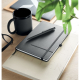 Mug noir et stylo bille noir posés sur un carnet à couverture rigide noire avec fermeture élastique, sur une table en bois à côt Mug noir et stylo bille noir posés sur un carnet à couverture rigide noire avec fermeture élastique, sur une table en bois à côt