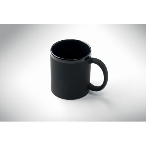 Mug en céramique noire à finition mate, avec une anse arrondie et un bord supérieur brillant, présenté de trois quarts sur fond 