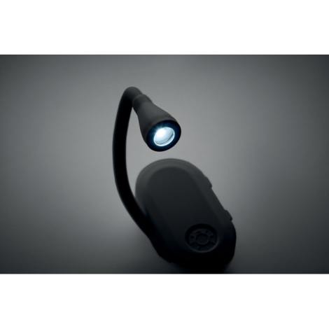 Gros plan sur une lampe de lecture noire allumée, avec bras flexible courbé maintenant la tête lumineuse au-dessus du boîtier ov