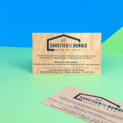 Deux cartes rectangulaires en bois clair avec logo et textes noirs. L'une est présentée verticalement, l'autre posée en diagonal