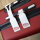 Deux étiquettes de bagage blanches avec logo SNCF Voyageurs sur une valise rigide rouge. L'une est fixée à la poignée, l'autre d