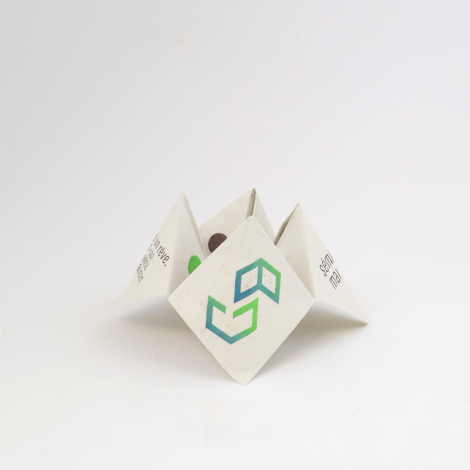 Cocotte en papier blanc ouverte sur fond blanc, avec logo géométrique vert et bleu sur la face centrale et textes imprimés sur l