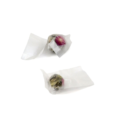 Gros plan sur deux boules de thé fleuri emballées individuellement dans des sachets transparents, laissant apparaître les feuill