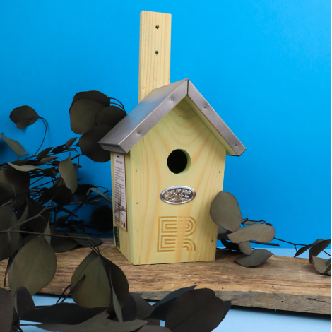 Nichoir à oiseaux en bois naturel personnalisé avec logo ER gravé sur la façade, toit métallique gris et trou d'envol rond. Prés