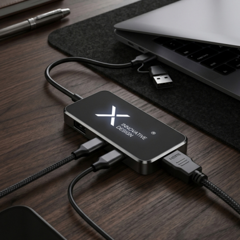 Hub USB noir personnalisé avec logo lumineux blanc, branché à un ordinateur portable et connecté à plusieurs câbles sur un burea