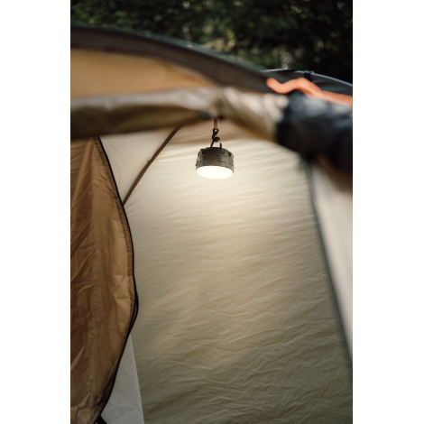 Lanterne de camping allumée, suspendue à l'intérieur d'une tente beige pour éclairer l'espace sous la toile.