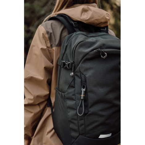 Vue rapprochée d'un sac à dos noir porté par une femme en veste marron, avec le câble de charge à mousqueton accroché à une sang
