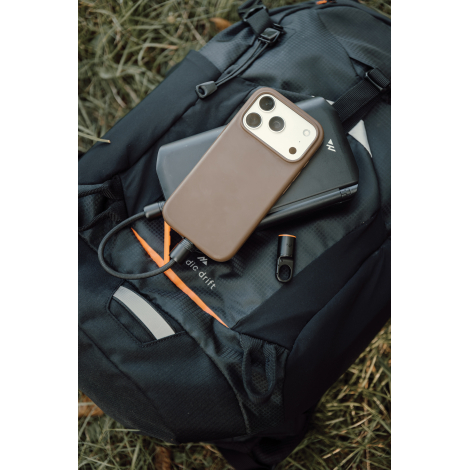 Smartphone à coque marron posé sur un chargeur noir pliable, avec câble de charge tressé branché au téléphone et mousqueton déta