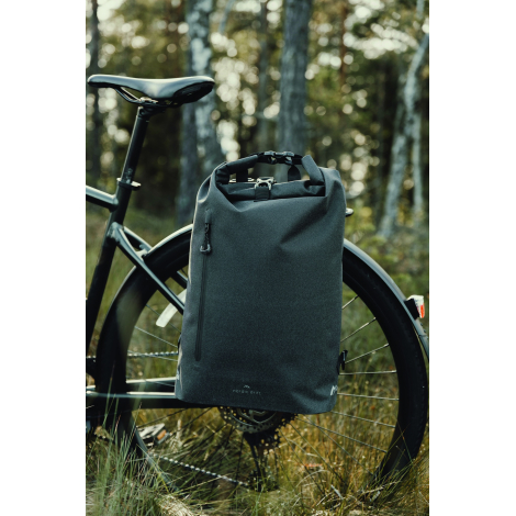 Sac noir à fermeture enroulable fixé sur le côté de la roue arrière d’un vélo, avec poche zippée verticale visible, dans un envi