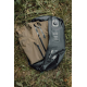 Sac de compression noir ouvert et posé dans l'herbe, contenant un sac beige à plusieurs fermetures zippées. La valve ronde, les 