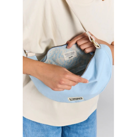Gros plan sur l'intérieur du sac demi-lune Inès bleu azur, ouvert par fermeture zippée, avec doublure à motifs floraux bleus, ét