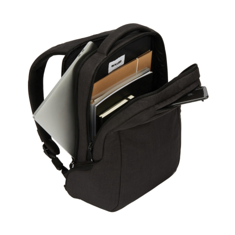 Sac à dos noir ouvert, présentant plusieurs compartiments de rangement contenant un ordinateur portable argenté, des documents, 