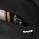 Gros plan sur une poche zippée du sac à dos noir, ouverte pour révéler plusieurs petits rangements contenant notamment une règle