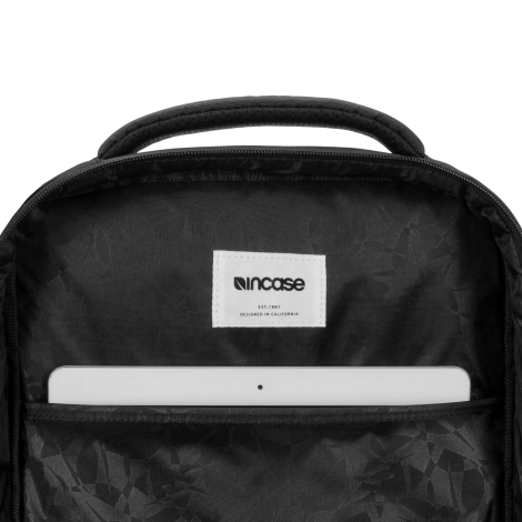 Gros plan sur un compartiment intérieur ouvert du sac à dos noir, avec doublure sombre à motifs géométriques et poche accueillan