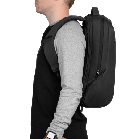 Un homme portant un haut noir à manches grises présente le sac à dos noir sur ses épaules, vu de profil. Le sac épouse son dos e