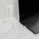 Chargeur blanc branché sur une prise murale, relié par un câble à un ordinateur portable noir ouvert sur un bureau blanc. Une fi Chargeur blanc branché sur une prise murale, relié par un câble à un ordinateur portable noir ouvert sur un bureau blanc. Une fi