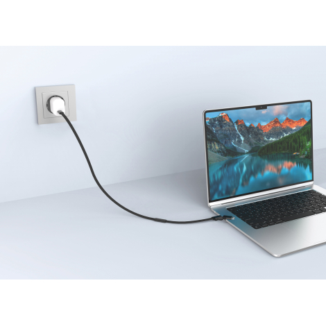Mise en situation d'un câble de recharge noir reliant un ordinateur portable à un chargeur secteur blanc branché sur une prise m