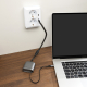 Câble de recharge rétractable Spira posé sur un bureau en bois, reliant un ordinateur portable à une prise murale USB-C, avec so Câble de recharge rétractable Spira posé sur un bureau en bois, reliant un ordinateur portable à une prise murale USB-C, avec so