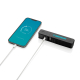 Appareil multifonction noir posé à côté d'un smartphone relié par un câble blanc à son port USB. L'écran bleu du téléphone affic Appareil multifonction noir posé à côté d'un smartphone relié par un câble blanc à son port USB. L'écran bleu du téléphone affic