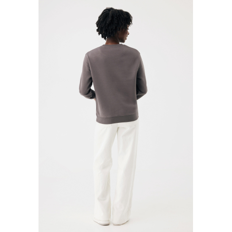 Une femme photographiée de dos porte un sweat gris taupe à col rond, avec une couture en demi-lune sous l'encolure et une bande 