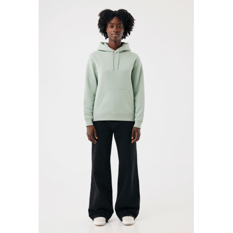Une femme aux cheveux crépus porte un sweat à capuche vert sauge avec cordons de serrage et poche kangourou, associé à un pantal