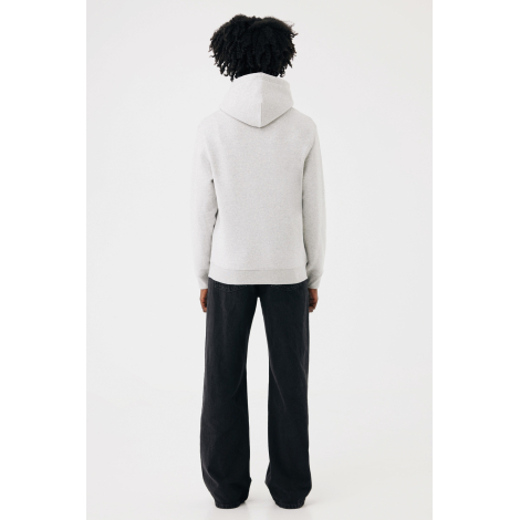 Une femme photographiée de dos porte un sweat à capuche gris clair chiné, avec une capuche à couture centrale et des finitions e