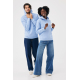 Un homme et une femme portent des sweats à capuche bleu ciel avec poches kangourou. L'homme relève sa capuche tandis que la femm Un homme et une femme portent des sweats à capuche bleu ciel avec poches kangourou. L'homme relève sa capuche tandis que la femm