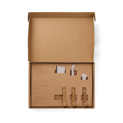 Coffret en carton kraft ouvert, présentant trois couteaux à fromage maintenus dans un insert découpé, avec leurs lames en acier 