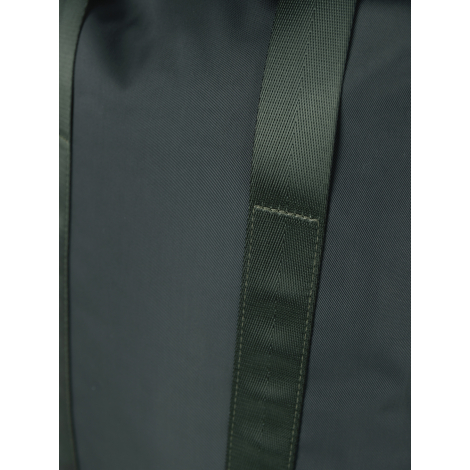 Gros plan sur une sangle vert foncé à tissage serré, cousue verticalement sur le tissu lisse d'un sac à dos, avec renfort rectan